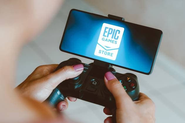 Logos displayed on smartphones in Brazil - 04 Dec 2023 In this photo illustration, the Epic Games Store logo is displayed on a smartphone screen as a person plays on a gaming gamepad. Brazil Copyright: xRafaelxHenriquex xSOPAxImagesx RAFAPRESS_04122023-09335