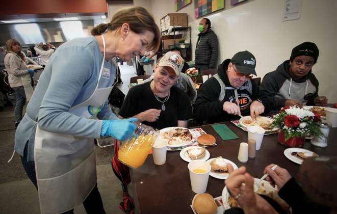 (231210) -- VANCOUVER, Dec. 10, 2023 -- A volunteer serves drink during the annual Christmas dinner at Union Gospel Mission (UGM) in Vancouver, British Columbia, Canada, on Dec. 9, 2023. (Photo by Xinhua) CANADA-VANCOUVER-CHRISTMAS-CHARITY DINNER LiangxSen 