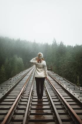 Creative Highlights Symbolbilder A woman in warm clothing contemplates a misty landscape while walking along a railway in Vancouver Island s woods. Model Released CamilleGirard_ID17696_535250_016 Copyright: xCamillexGirardx