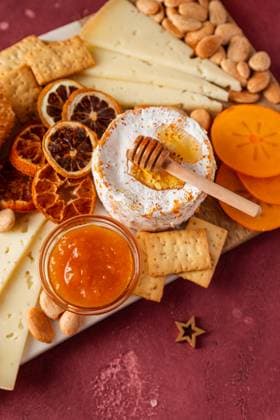Gourmet cheese platter with honey, dried fruit, and nuts on a rustic table. Model Released CintiaViudez_ID18056_543210_006 Copyright: xCintiaxViudezx RECORD DATE NOT STATED