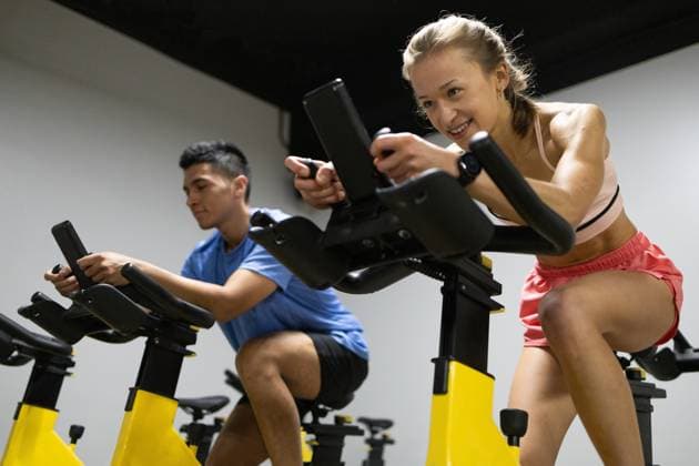 Two focused cyclists engage in a spinning class, showcasing their fitness routine within a gym environment. Model Released DavidMunoz_ID17833_538074_023 Copyright: xDavidxMunozx