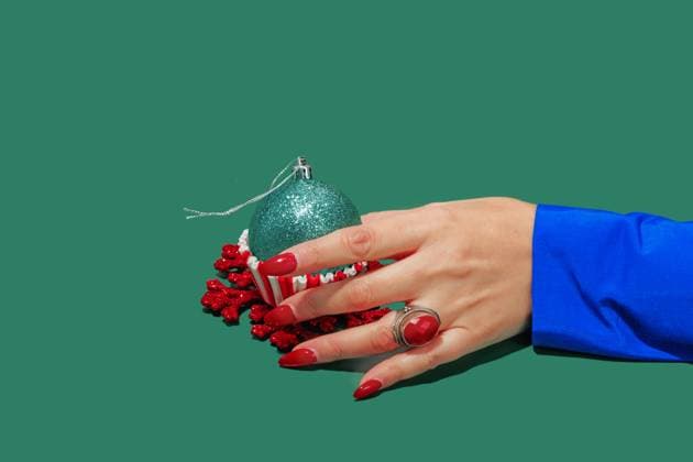 Creative Highlights Symbolbilder A hand adorned with a red ring holds a sparkly green Christmas ornament cupcake, against a green backdrop Model Released Rodobot_ID18123_544759_005 Copyright: xRodobotx