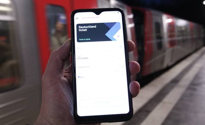 A man on a train platform is holding his smartphone with a Germany ticket in the Hamburg public transport app Symbol image Symbol photo Germany ticket Eppendorf Hamburg