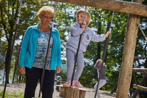 A little girl playing on the wooden attraction in the playground under the supervision of her grandmother 193895 ,model released, Symbolfoto RECORD DATE NOT STATED