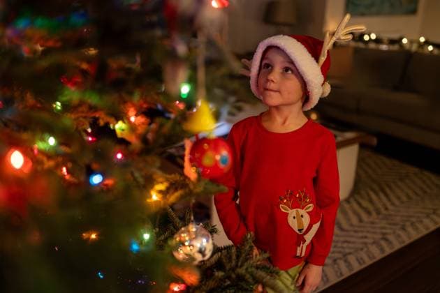 Young boy wearing a Santa hat looking at his Christmas tree United States, Connecticut, Southington R_ASOG23121882-1309117-01 ,model released, Symbolfoto