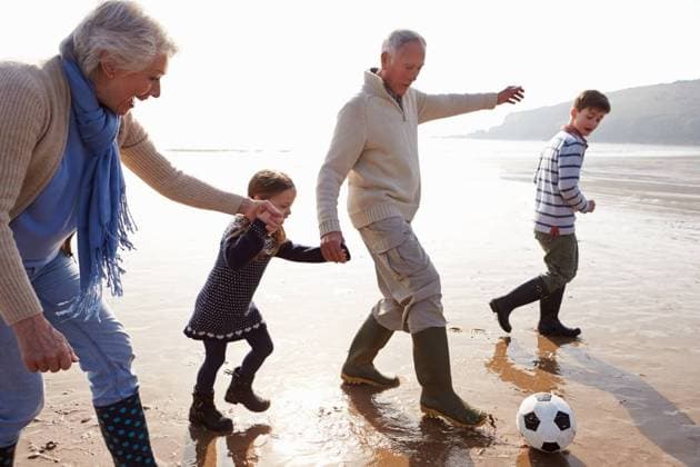 RECORD DATE NOT STATED Grandparents With Grandchildren Playing Football On Beach