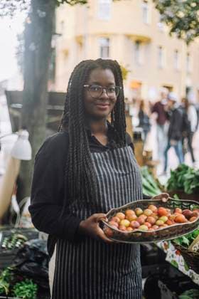 IMAGO Creative, Jahreszeit Sommer, Food, Pflaume Portrait of smiling female vendor holding tray of fresh plums while standing at farmer s market Sweden, Stockholm, model released Copyright: xMaskotx , MA105823 MA105823