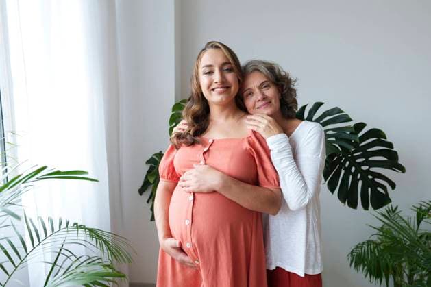 Smiling woman standing with pregnant daughter at home model released, Symbolfoto property released, AAZF01325