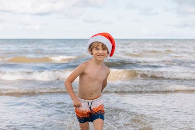 Creative Highlights Symbolbilder Smiling boy wearing Santa hat running at beach model released, Symbolfoto, EVKF00083