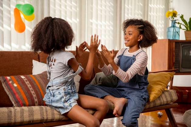 Happy girls playing clapping game on sofa at home model released, Symbolfoto property released, IKF01445