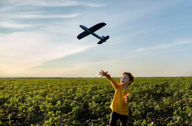 Carefree boy playing with toy airplane in agricultural field under sky model released, Symbolfoto, MBLF00167