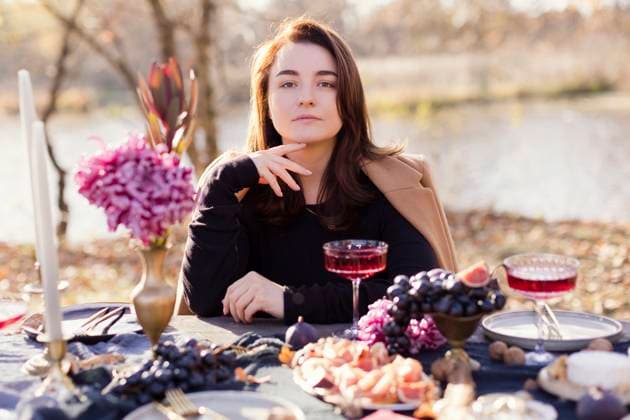 Creative Highlights Symbolbilder Woman with hand on chin sitting at table and celebrating thanksgiving in forest model released, Symbolfoto, ONAF00697