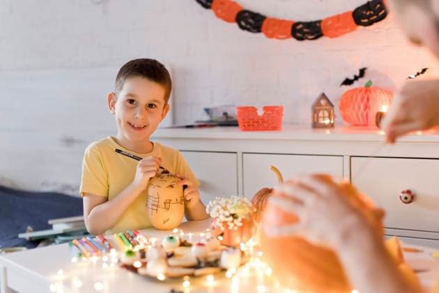 Smiling boy drawing on pumpkin with father at table model released, Symbolfoto property released, ONAF00704