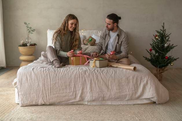 Smiling couple tying ribbons on Christmas presents at home model released, Symbolfoto property released, VPIF08961