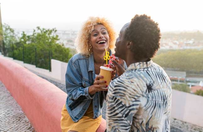 Creative Highlights Symbolbilder Young transgender woman enjoying juice with boyfriend sitting on wall model released, Symbolfoto, VRAF00264