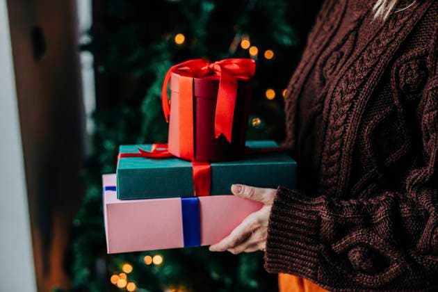 Woman wearing sweater and holding Christmas gifts at home model released, Symbolfoto, VSNF01482