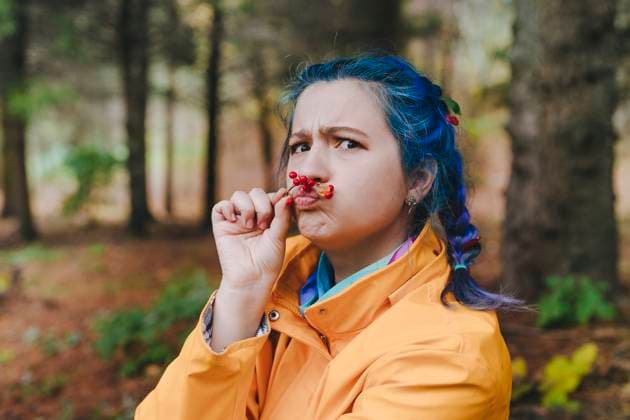 Playful woman smelling berries in forest model released, Symbolfoto, YTF01388