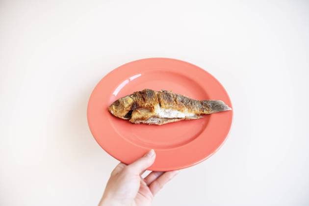 A whole fried carp with a fried crust, served on a bright red plate. A hand holds a plate on a white background. A whole fried carp with a fried crust, served on a bright red plate. A hand holds a plate on a white background Copyright: xZoonar.com SergiyxArtsabax 20398047