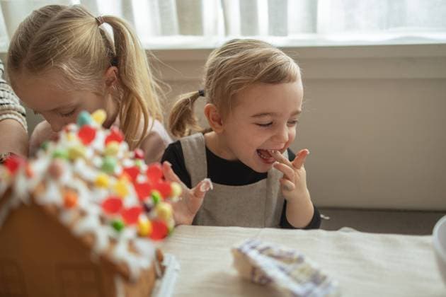 Girl giggles while decorating a gingerbread house with family Vancouver, British Columbia, Canada CR_LJRI231229-1311488-01 ,model released, Symbolfoto