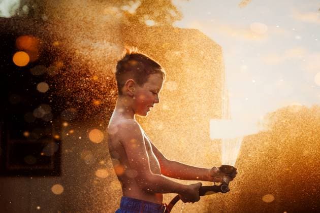 Creative Highlights Symbolbilder Boy playing in water in front of golden light Tulsa, Oklahoma, United States CR_KRRY231229-1313867-01 ,model released, Symbolfoto