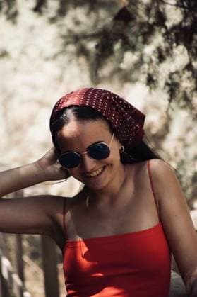 Creative Highlights Symbolbilder A shallow focus of a young female wearing a red top with sunglasses and a bandana laughing in a park 854120 ,model released, Symbolfoto RECORD DATE NOT STATED