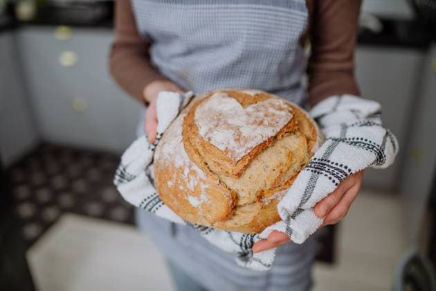 Close-up of woman holding homemade sourdough bread, cooking at home concept. A close-up of woman holding homemade sourdough bread, cooking at home concept. model released Copyright: xx Eco_Lifestyle_2022_224