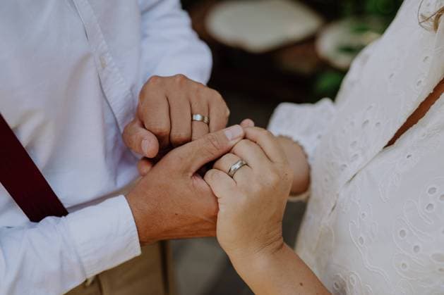 Close-up of bride and groom holding hands with wedding rings at reception outside in the backyard. A close-up of bride and groom holding hands with wedding rings at reception outside in the backyard. model released Copyright: xx HHH BACKYARD WEDDING 2022 HHH 137