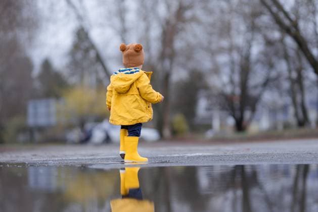 Happy little boy jumping in puddle after rain in autumn day. Happy little boy jumping in puddle after rain in cold autumn day. model released Copyright: xx HHH MATUS WALK 2022 HHH 064