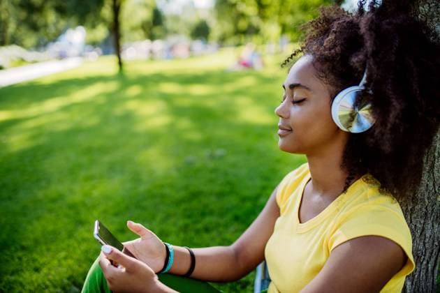 IMAGO Creative: Sommer, Sommertage im Garten Multiracial girl sitting in grass and enjoying music in headphones, side view. Multiracial girl sitting in a grass and enjoying music in headphones, side view. model released Copyright: xx HHH SOLO TZ KYARA PORTRAITS 2022 HHH 166
