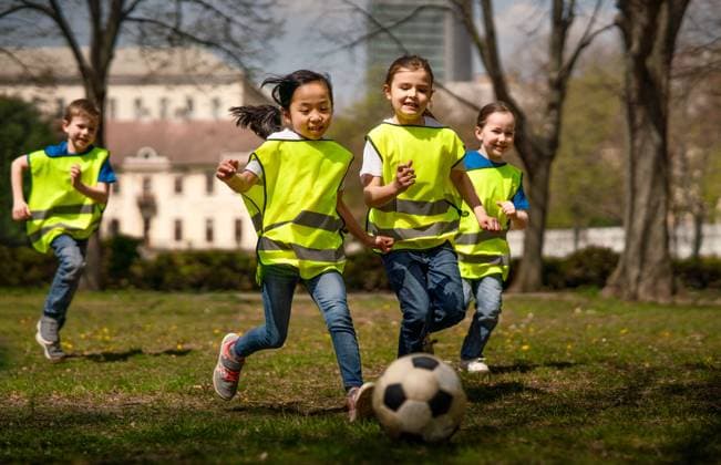 Small children playing football outdoors in city park, learning group education concept. Happy small children playing football outdoors in city park, learning group education concept. model released Copyright: xx CITY OUTDOOR EDUCATION 2021_097_1