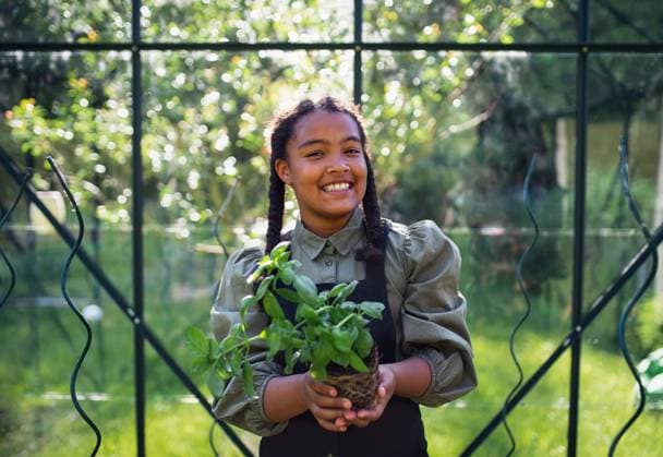 IMAGO Creative: Garten, Anbau im Gewächshaus Happy small girl gardening in greenhouse outdoors in backyard, looking at camera. A happy small girl gardening in greenhouse outdoors in backyard, looking at camera. model released Copyright: xx Man at home Victor 2021 170