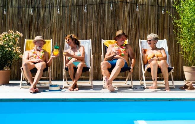 Group of cheerful seniors sitting by swimming pool outdoors in backyard. Group of cheerful seniors sitting by swimming pool outdoors in backyard, relaxing. model released Copyright: xx Summer_Splash_Seniors_2020_019