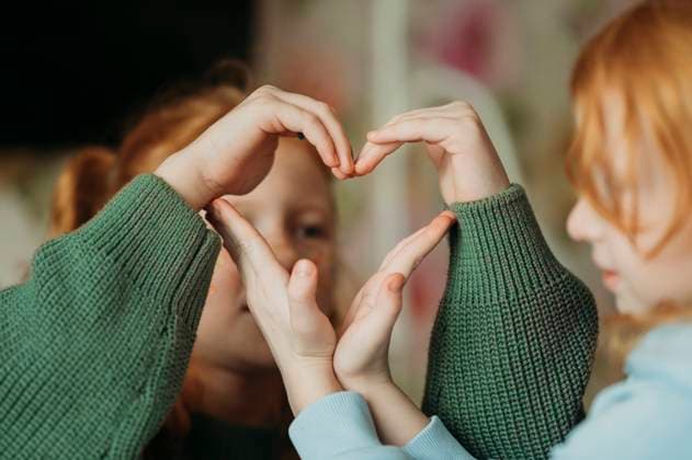 Sisters making heart shape with hands at home model released, Symbolfoto, ANAF02586