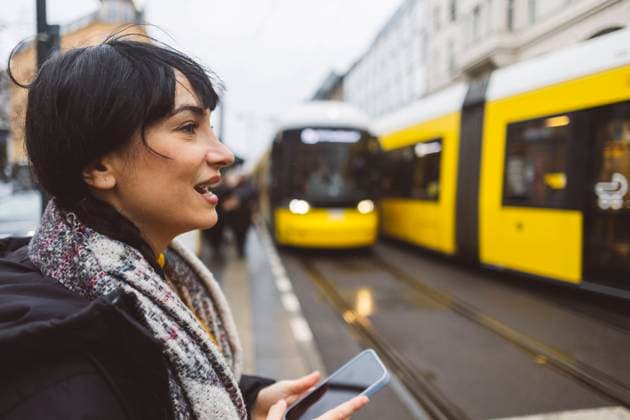 Happy woman holding smart phone and waiting at tram station model released, Symbolfoto, JCCMF11092