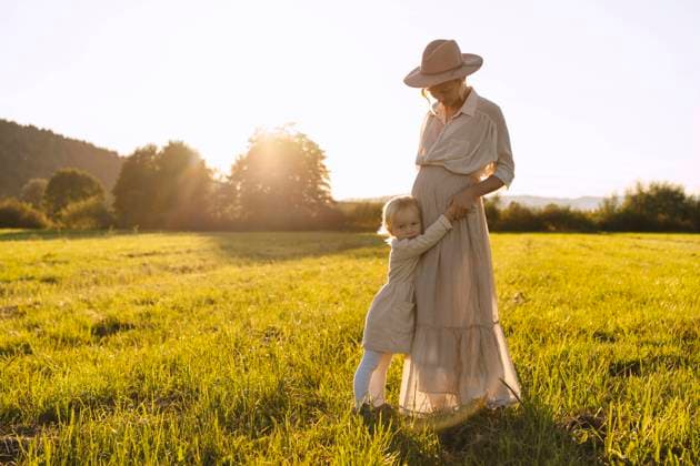 Pregnant mother embracing and holding daughter s hand in field at sunset model released, Symbolfoto, NDEF01511