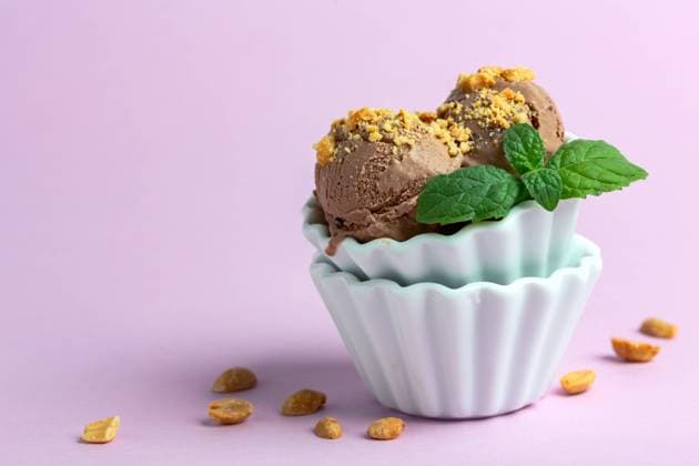 Chocolate ice cream balls with peanuts. Homemade chocolate ice cream with peanuts in a porcelain bowl with a sprig of mint on a pink background, selective focus. Copyright: xZoonar.com MarinaxSaprunovax 20892221