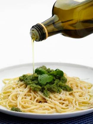 Bottle of olive oil pouring over plate of pesto pasta Milan, Lombardy Metro City of Milan, Italy, 21.12.2023, TTBB_BLD185626.jpg, bottle, close up, color image, copy space, focus on foreground, food and drink, leaf, motion, nobody, oil, olio, olive oil, pasta, pesto, photography, plate, pouring, spaghetti, spaghetti al pesto, studio shot, vertical, white background, carbohydrate, close-up, closeup, color, colour, container, crockery, dish, dishware, foliage, food, italian, movement, negative space, plant, pour, studio, tableware, vegetation, white space, Copyright: xWalterxZerlax