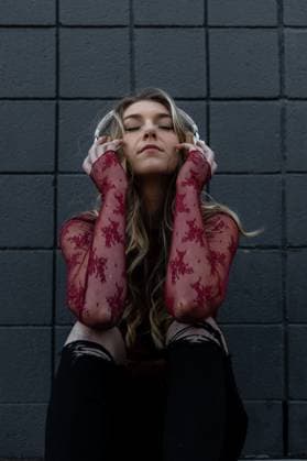 Creative Highlights Symbolbilder Woman sitting next to wall listening to music on headphones San Diego, California, United States R_VCOZ24012638-1341887-01 ,model released, Symbolfoto