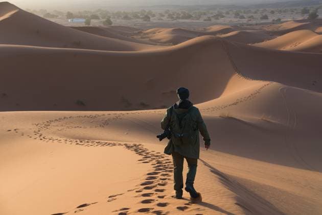 Creative Highlights Symbolbilder Back view of unrecognizable photographer wanders the stunning dunes of the Merzouga desert (Erg Chebbi) in Morocco, capturing its beauty at sunrise, with Fez city to explore next. Model Released TeoTarras_ID18957_564299_007 Copyright: xTeoxTarrasx RECORD DATE NOT STATED