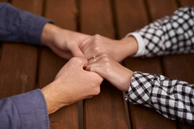 Close up on a man and a woman holding hands at a wooden table. Loving couple holding hands on table, man friend husband support woman wife expressing love feelings, trust care honesty in interracial relationship concept, close up view Close up on a man and a woman holding hands at a wooden table ,model released, Symbolfoto Copyright: xZoonar.com AndrIixKovnirx 21114316 ,model released, Symbolfoto ,property released