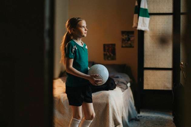 Determinant female athlete with soccer ball standing in bedroom at home Sweden, Gothenburg, model released, property released Copyright: xMaskotx , MA106780 MA106780