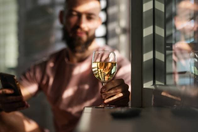 Young man looking at glass with white wine, New Year s resolutions, drink less alcohol healthy lifestyle without alcoholic drinks. Young man looking at a glass with white wine, New Year s resolutions, drink less alcohol healthy lifestyle without alcoholic drinks. model released