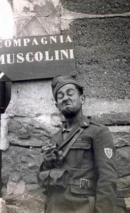 Portrait of an Italian soldier who is posing with a humorous grimace. He is wearing a uniform and is holding a cigaret. Behind him can be seen a sign on the wall on which is written Compagnia Muscolini , 07 1938 (b w photo) 1250076 Portrait of an Italian soldier who is posing with a humorous grimace. He is wearing a uniform and is holding a cigaret. Behind him can be seen a sign on the wall on which is written Compagnia Muscolini , 07 1938 (b w photo) by Unknown photographer, (20th century); (add.info.: Unidentified Author Spain); Fratelli Alinari Museum Collections, Florence, Italy. Copyright: xFratellixAlinarixMuseumxCollections,xFlorence,xItalyx xBridgemanxImagesx 1250076