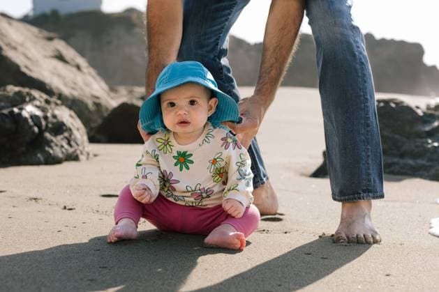 Creative Highlights Symbolbilder Baby girl in a sunhat unsure as she sits on the sand at the beach Malibu, California, United States CR_ANWHER240207-1349296-01 ,model released, Symbolfoto