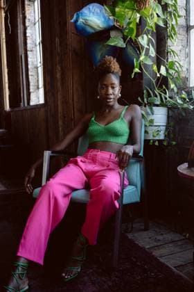 Young Black woman in colorful outfit poses in chair by window Kansas City, Missouri, United States CR_SXFI24021225-1350520-01 ,model released, Symbolfoto