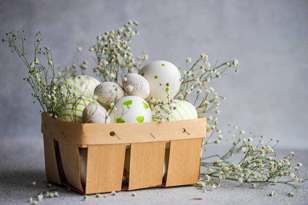 A wooden basket filled with patterned Easter eggs, adorned with delicate gypsophila flowers on a textured background Model Released AnnaBogush_ID19528_579166_001 Copyright: xAnnaxBogushx