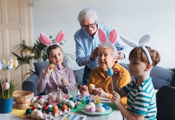 Grandmother with little kids decorating easter eggs at home. Tradition of painting eggs with brush and easter egg dye. Grandmother with little kids decorating easter eggs at home. Tradition of painting eggs with brush and easter egg dye. Concept of family easter holidays. model released