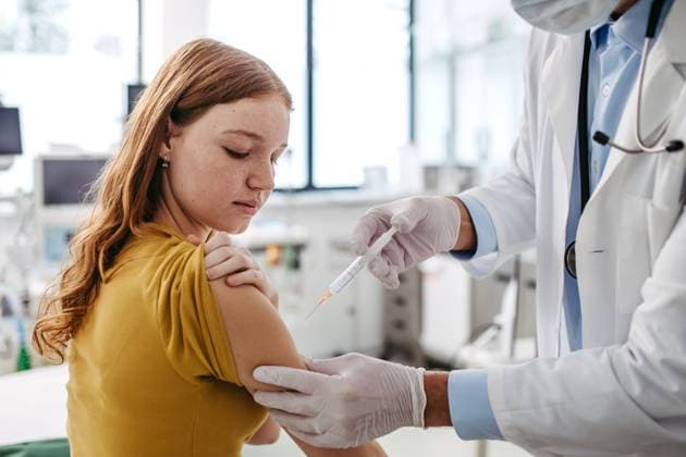 Doctor, pediatrician injecting vaccine into teenage girl arm. Concept of preventive health care and vaccination for teenagers. Doctor, pediatrician injecting vaccine into teenage girl arm. Concept of preventive health care and vaccination for teenagers, immunisation. model released
