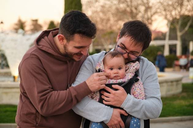 Homosexual happy couple playing with their baby in a baby carrier. Madrid, Community of Madrid, Spain CR_CRVI240216-1352007-01 ,model released, Symbolfoto