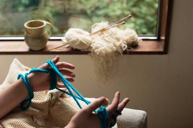 Teen girl touching blue yarn by window with mug of tea Seattle, Washington, United States CR_AAGC240220-1354564-01 ,model released, Symbolfoto